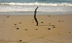 A stick standing up in the sand and giving a shadow